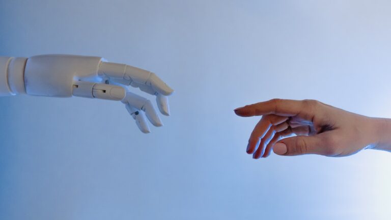 Featured image for the article best ai writing software showing two hands, one robotic and one human, trying to reach each other.